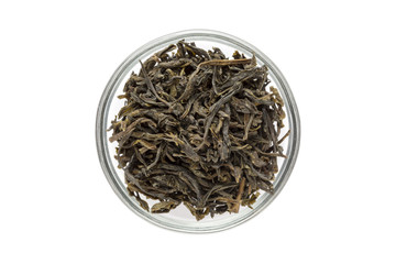 Organic Green Tea (Camellia sinensis) dried long leaves in glass bowl isolated on white background. Macro close up. Top view.