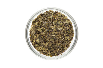 Organic Green tea (Camellia sinensis) Tea bag cut, dried leaves, in glass bowl isolated on white background. Macro close up. Top view.