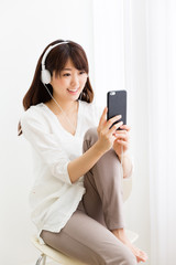 Naklejka premium attractive asian woman listening music