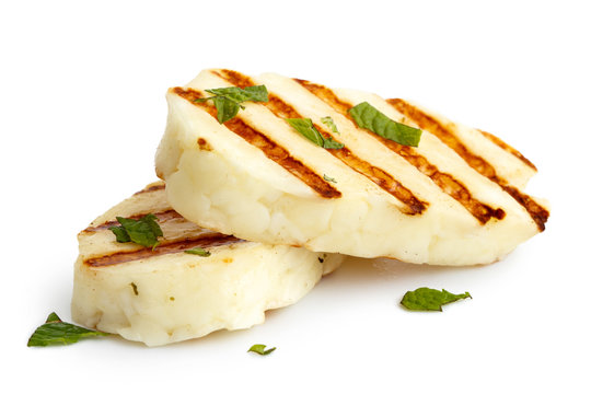 Two grilled slices of halloumi cheese isolated on white in perspective. With grill marks and mint.