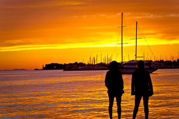 People silhouettes at golden sunset at sea
