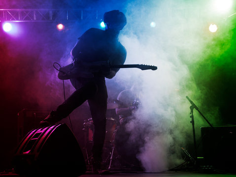 Silhouette of guitar player on stage.