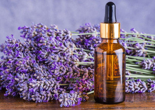 Fototapeta Lavender oil bottle on wood background.Essential oil, natural remedies.