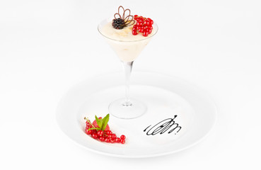 Vanilla panna cotta dessert with red currants and blackberries on a white background