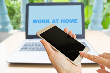 hand hold smart phone on blur Laptop