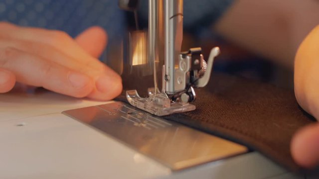 sewing machine is stitching black fabric close-up