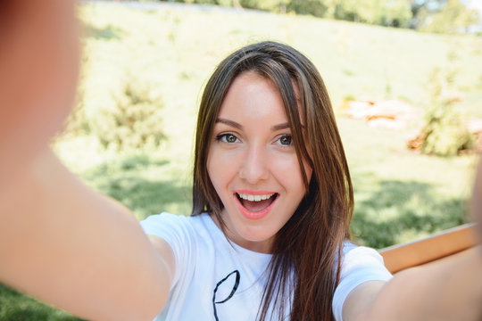 POrtrait of a smiling young girl making selfie photo in park
