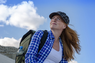 Young beautiful woman backpacker with red hair and freckles traveling in the desert. Sandy dunes and blue sky on sunny summer day. Travel, adventure, freedom concept. Toned.