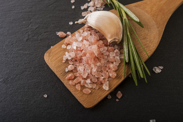 Salt, pepper, garlic and rosemary on a chopping board
