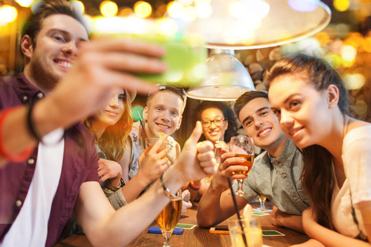 happy friends with smartphone taking selfie at bar