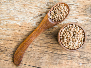 Dried coriander seeds on wood background