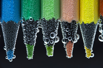 Colorful pencils in water with bubbles