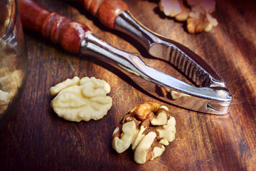 Walnut kernels and vintage nutcracker on a wooden scratched board. Selective focus