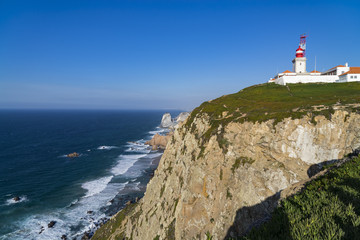 Fototapeta na wymiar Cliffs and lighthouse of Cabo da Roca on the Atlantic Ocean in Sintra, Portugal, the westernmost point on the continent of Europe, where the land ends and the sea begins.