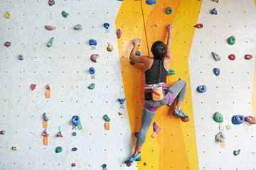 Back view of sportswoman climbing in the gym - obrazy, fototapety, plakaty