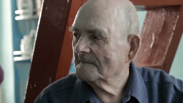 Elderly man sitting observing a room and thinking or remember something