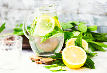 Water with lemon, mint and cucumber in glass,light background
