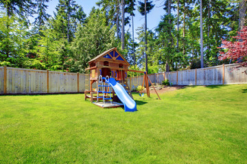 Play kids ground area with chute in fenced backyard.