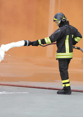 Fireman with an extinguisher with foam under the Orange smoke