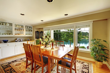 Bright dining room with wooden table set, white cabinets and green walls.