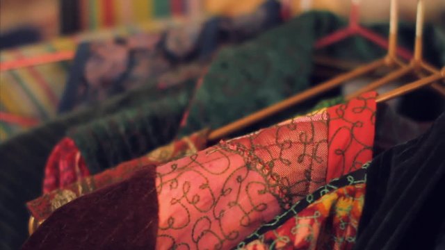 Close up shot of wide range of colorful traditional national uzbek  robes hanging in a store or souvenir shop on hangers in Uzbekistan. Rack focus.