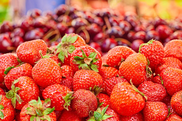 Сounter on the market: strawberry in the foreground and cherries in the background  