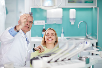 Smiling female woman with dentist looking at dental snapshot