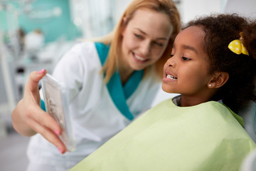Sweet black girl patient showing in mirror her teeth