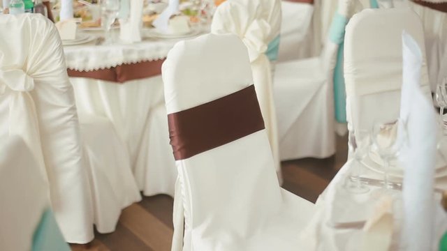 Decorated wedding hall prepared for celebration. Chairs in cloth decoration with colored ribbons