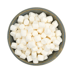 Small marshmallows in an old stoneware bowl top view isolated on a white background.