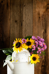 Sonnenblumen und Astern in einer Gießkanne