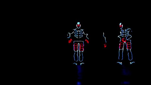 4 people dancing in costumes of LEDs 