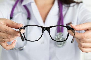 Female oculist doctor hands giving pair of glasses. Good vision