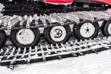 Fototapeta na wymiar snowcat detail at winter snow storm, caterpillar and wheel detail