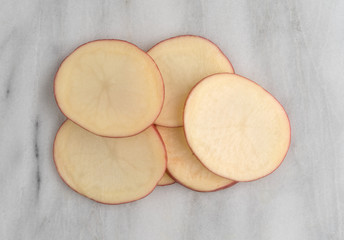 Sliced red potatoes on a gray marble cutting board.