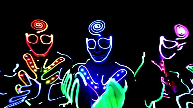4 people dancing in costumes of LEDs 