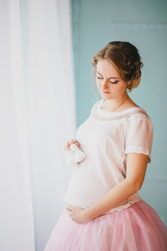 Young beautiful pregnant woman posing near window