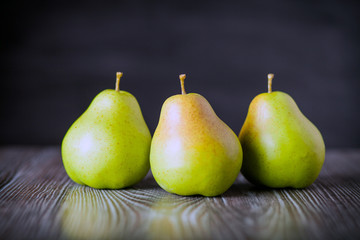 Fototapeta na wymiar Green pears on wooden table dark background front view