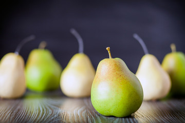 Green pears on wooden table dark background front view
