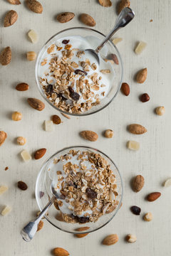 Granola with yoghurt, nuts and fruits in glass bowl on dark background. Delicious, healthy sweet dessert for breakfast. Cereal, muesli.  Copy space, closeup.
