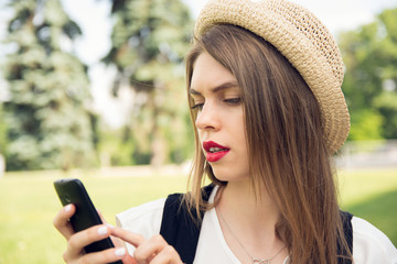 Young hipster girl with trendy look chatting on smart phone