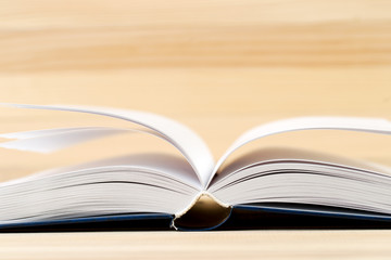 Open hardback book on wooden table. Back to school. Copy space