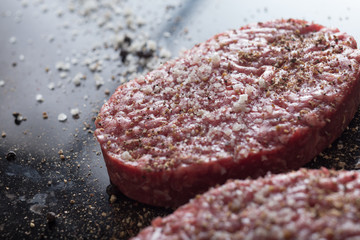 Meat for burgers, grilling, barbecue, bbq. Fresh, spicy, uncooked, delicious beef for hamburgers on dark background with copy space closeup
