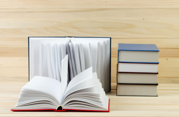 Open book, stack of hardback books on wooden table. Back to school. Copy space