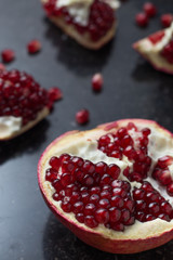 Red juicy pomegranate on dark marble background. Healthy, antioxidant, fresh, gourmet, delicious, organic fruit. Ingredient for grenadine. Close-up and copy space.