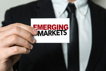 Business man holding a card with the text: Emerging Markets