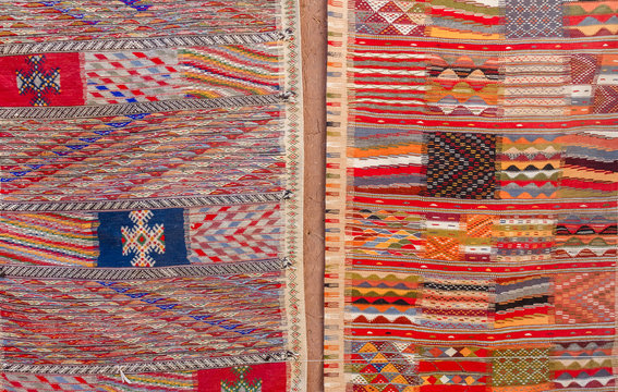Colorful Moroccan Berber carpets hanging on adobe wall
