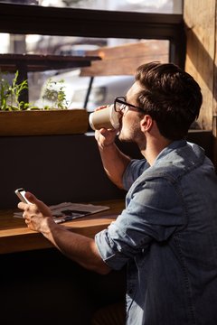 Man drinking coffee and using smartphone