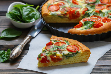 Summer outdoor tart, pie of fresh vegetables - tomatoes, spinach and red onion with cream and cheese. Selective focus
