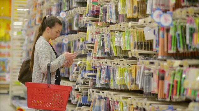 young beautiful woman buying stationery for school, beautiful mother choose pens and tools in a supermarket for her children
